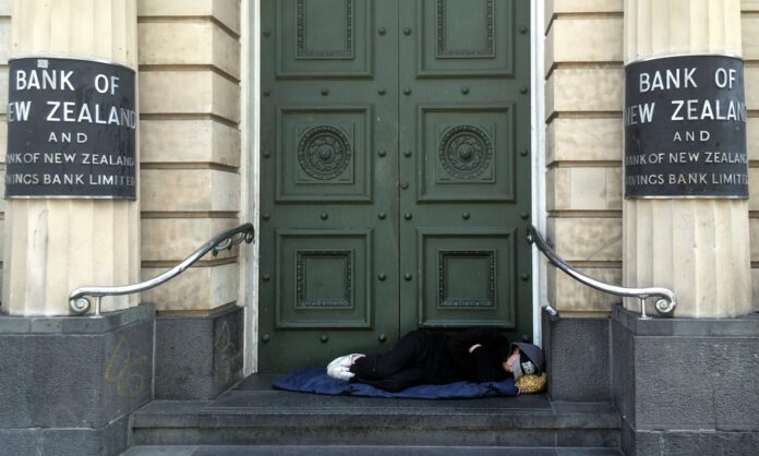 A person sleeping rough in a bank doorway.