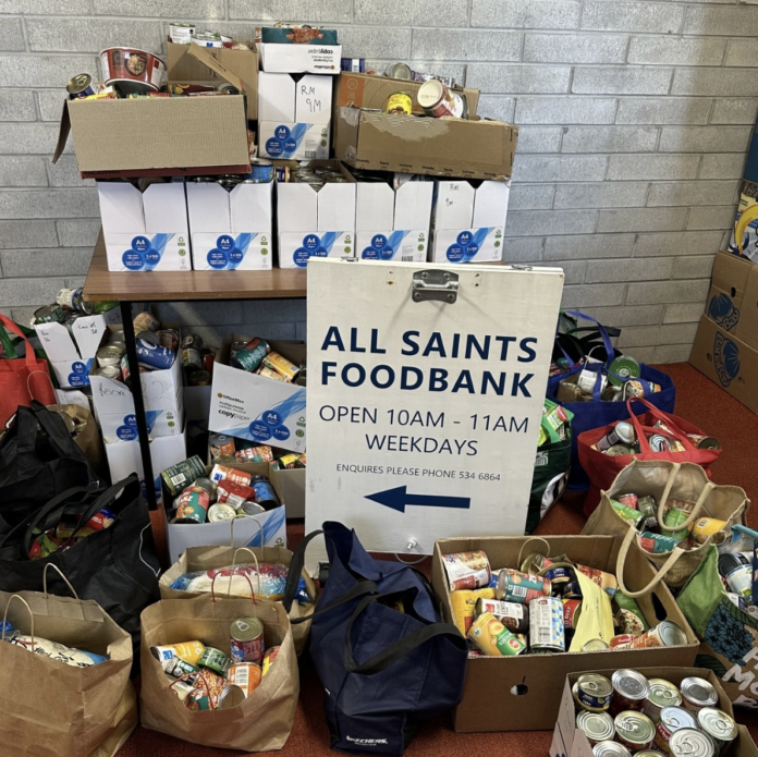Donated food stacked around the All Saints Foodbank sign in Howick