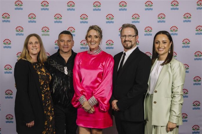 Five Auckland councillors standing in a row in front of a patterned Auckland Council backdrop