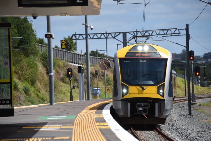 A blue and yellow Auckland electric train stopped at Meadowbank station platform on the Eastern Line.