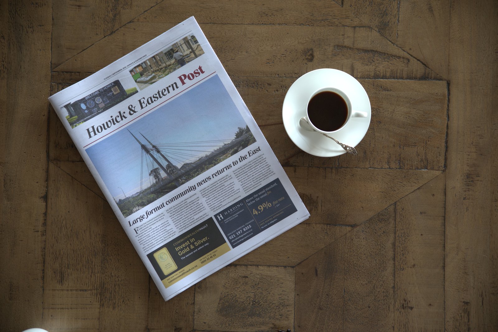 The printed Howick & Eastern Post lying on a wooden table beside a cup of coffee