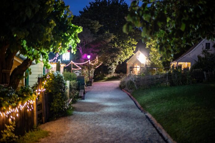 Historic buildings and gardens lit by light installations at night at the Howick Historical Village