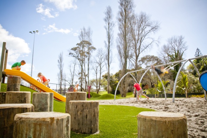 Children play on a slide, log steppers and a climbing frame at an Auckland Council playground