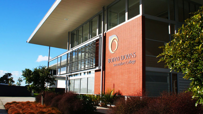 The main entrance of Botany Downs Secondary College, a brick and glass building carrying the school's name and logo.