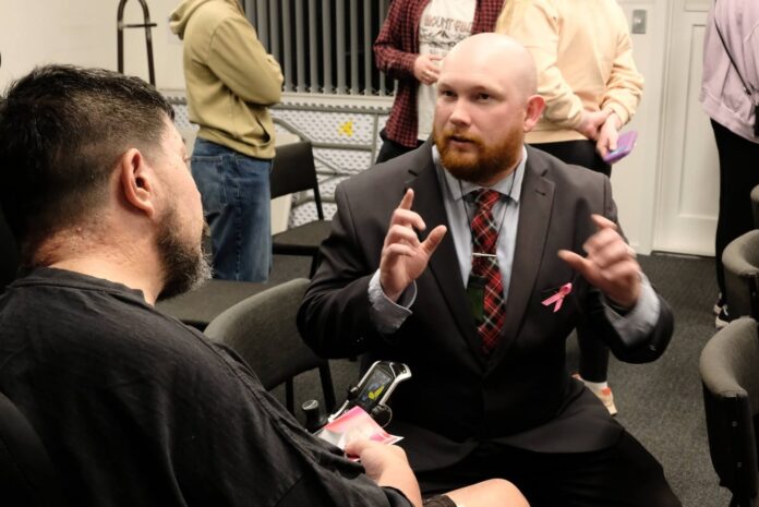 Campbell Matthews sitting with a group of people at a community meeting in Highland Park.