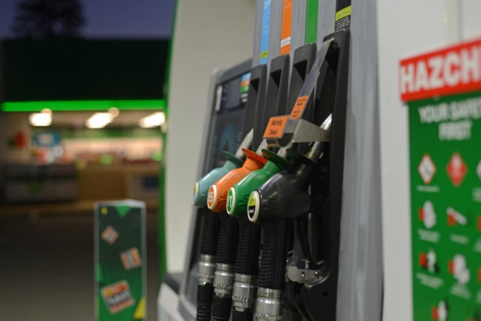 Petrol and diesel nozzles racked on a service station pump at dusk.