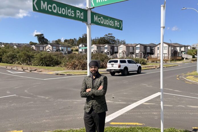 Adarshpreet Bhullar stands with arms folded beneath McQuoids Rd street signs at a Flat Bush intersection.