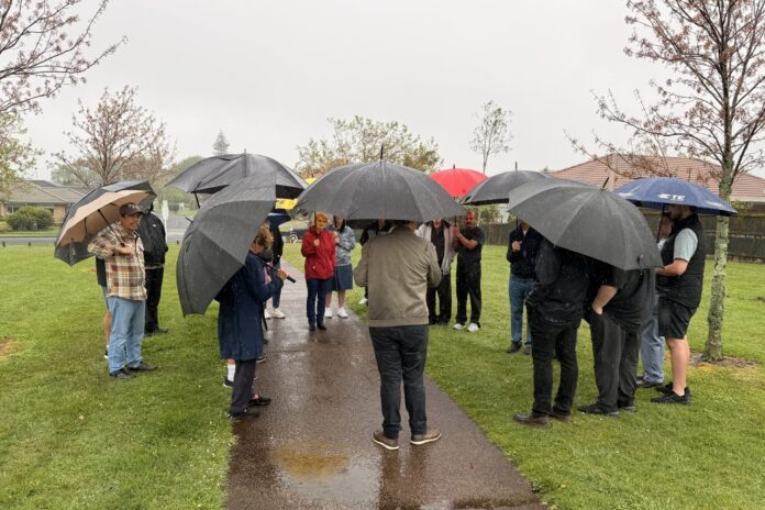 Residents with umbrellas stand along the wet path at Tarnica Park in Northpark.